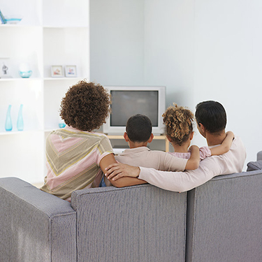 parents-with-daughter-4-5-years-and-son-6-7-years-sitting-on-sofa-watching-television-rear-view-stockbyte.jpg